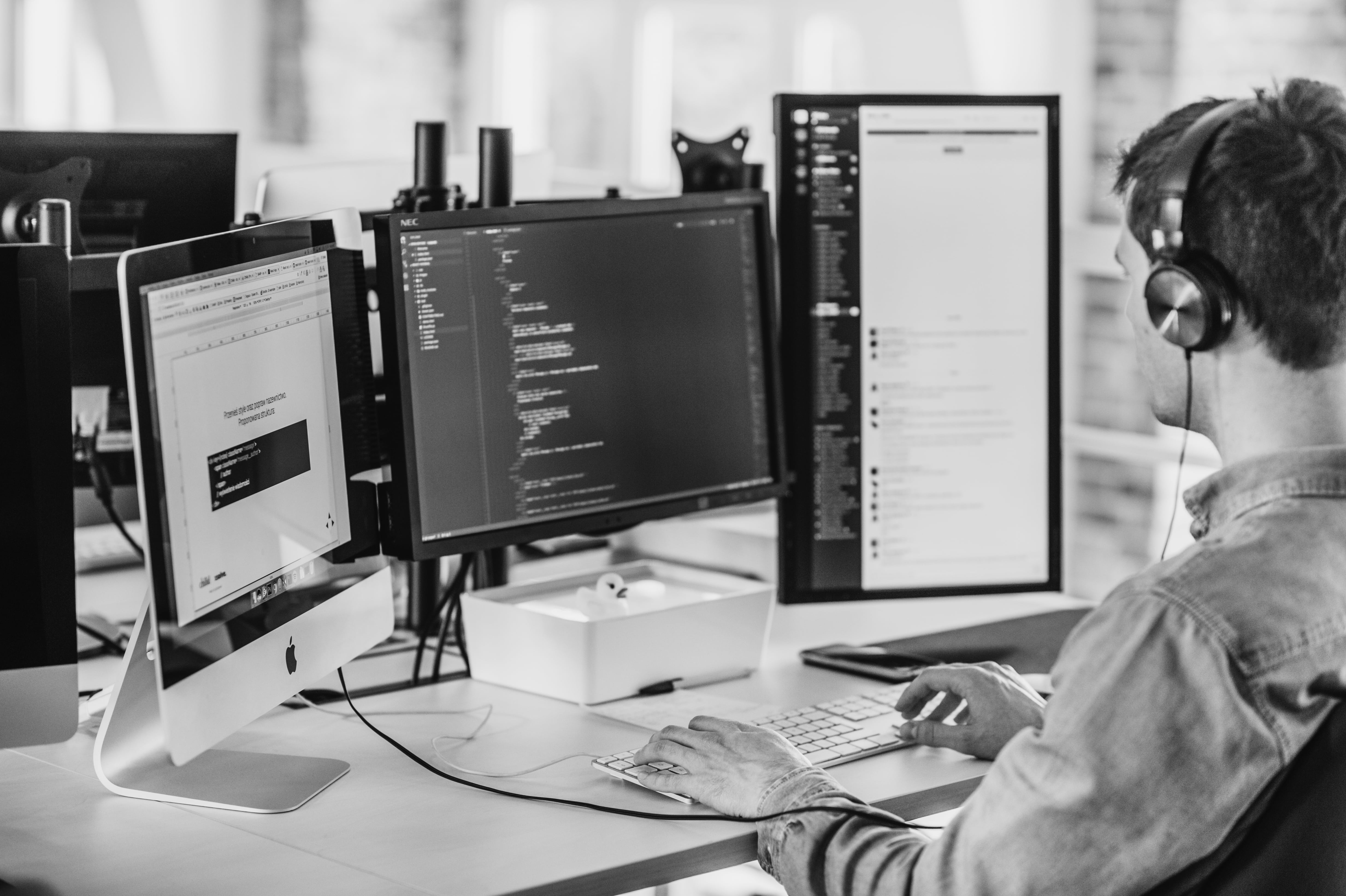 Person programing, having 3 monitors in front