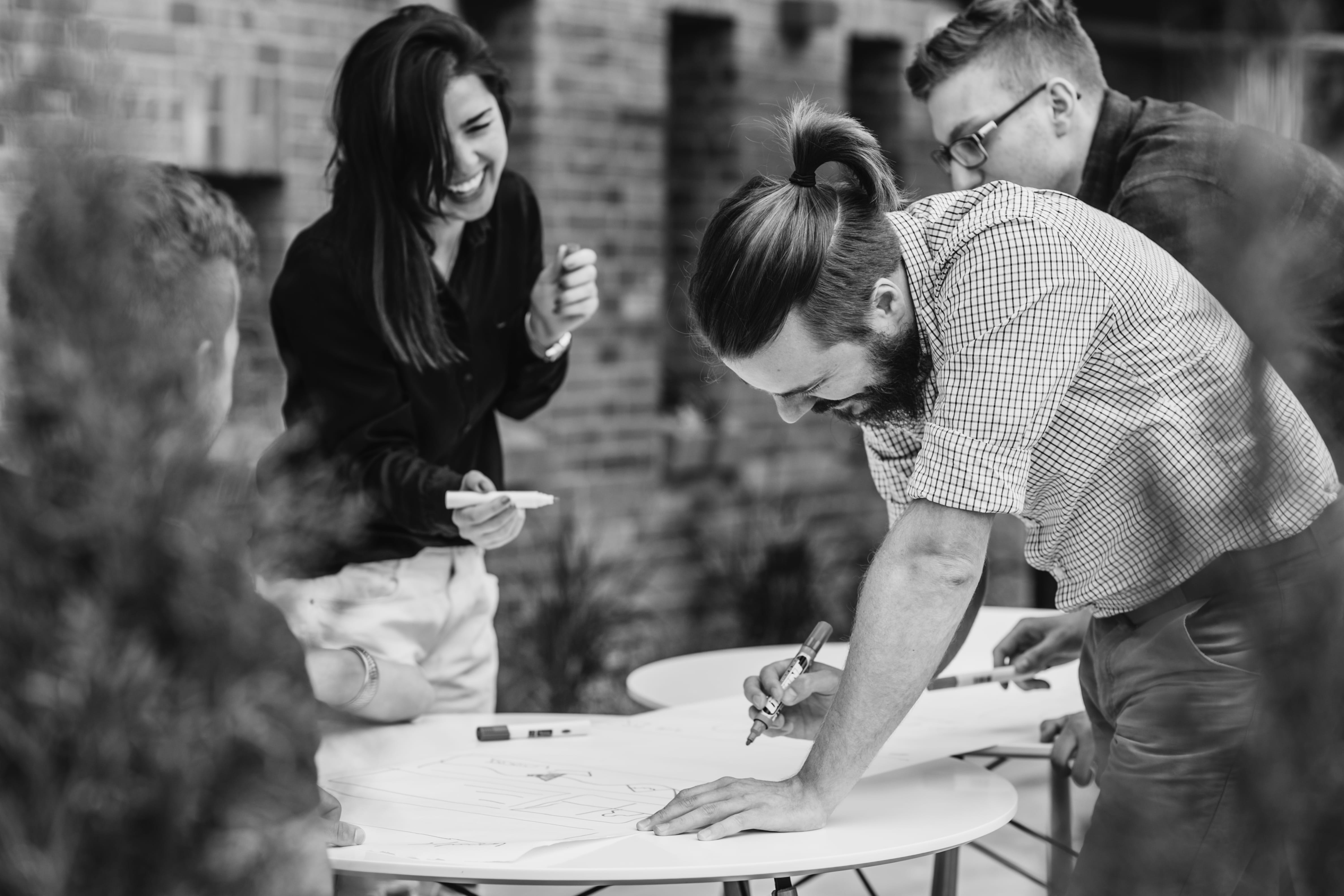 People drawing on a sheet of paper places on a table