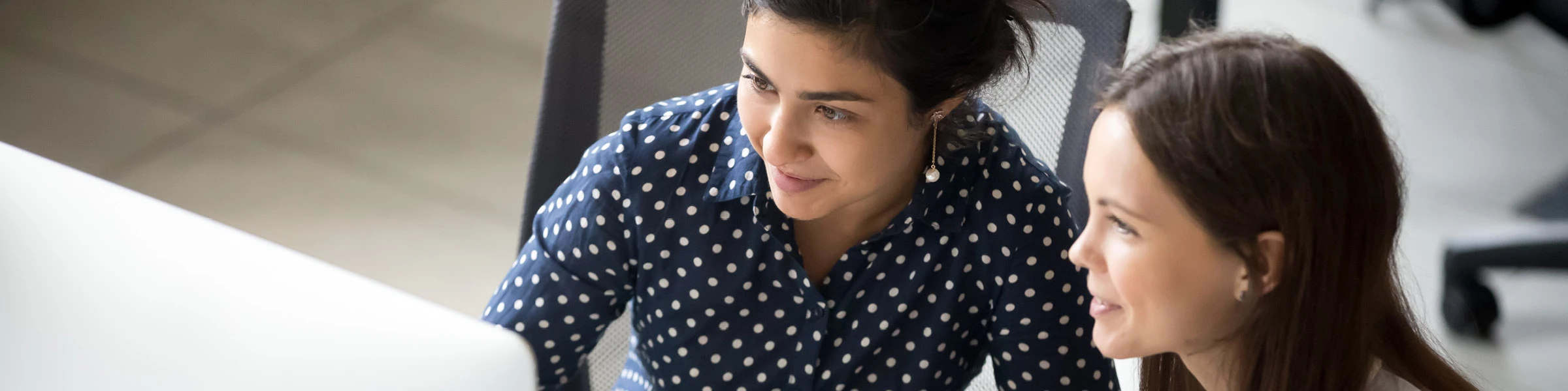 Two female colleagues working on a computer