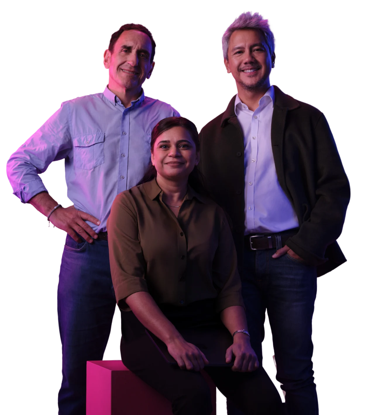 Three professionals posing together against white background with purple lighting, woman seated in front of two men.