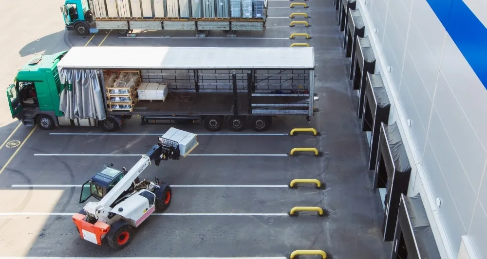 A tractor carrying boxes of stock loads up a larger truck