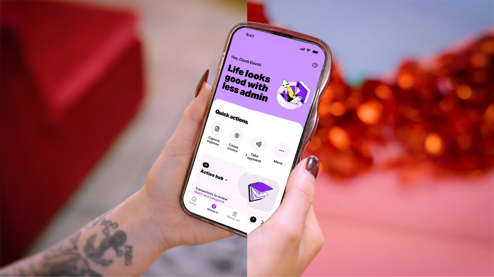 Hand with tattoo holding smartphone displaying financial app with "Life looks good with less admin" and quick action buttons.