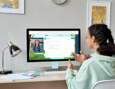 A teenage girl is working on a computer at a desk - on screen there is an Explore Learning tutor with an example question.