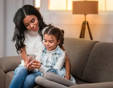 Mum showing her daughter something on a mobile phone.