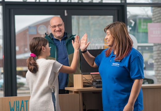 A child high fives with their tutor as the caregiver watches.