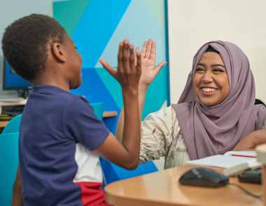 A child and their tutor high fiving.