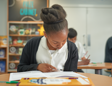 A young girl reading an 11 Plus exam book at a desk