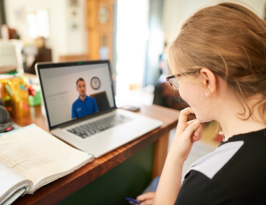 A girl sitting in front of a laptop with an Explore tutor on screen.