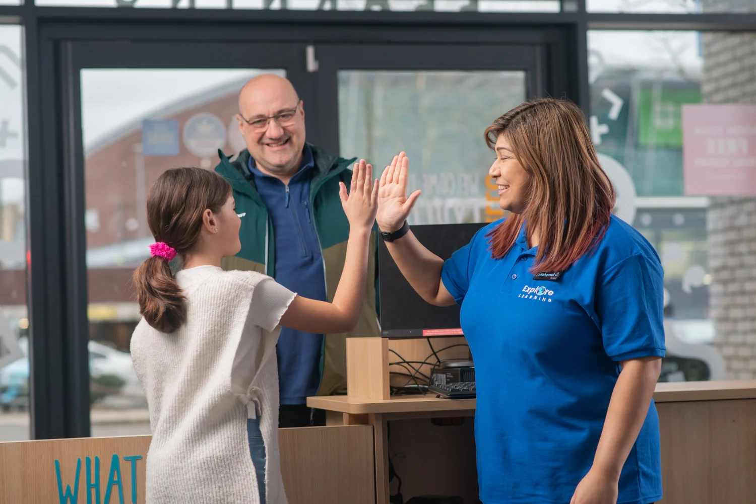 Happy parent as tutor high-fives child in an Explore Learning centre
