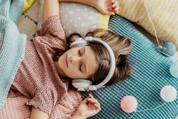 Little girl relaxing listening to music in bed