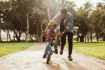 Child and father riding a bike in the park