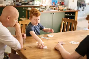 2 boys playing cards with their dad on the dining table