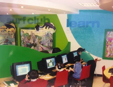 Picture of the 1st centre with children using computers and a tutor helping them