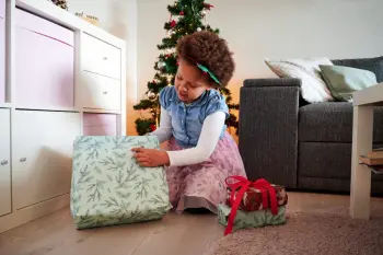 young black girl opening up a Christmas gift in soft green paper. 