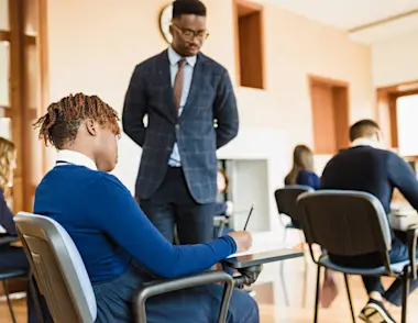 Invigilator stands over student doing an exam