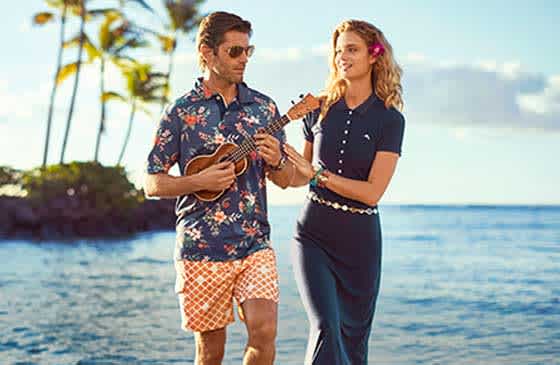 Man playing a ukulele and woman touching his arm standing on an exotic island