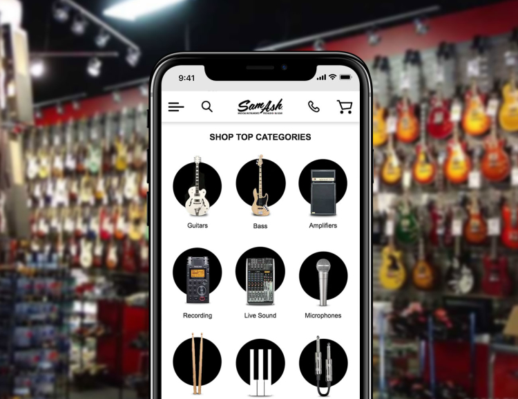 Sam Ash website shown on mobile device with guitar wall in the background