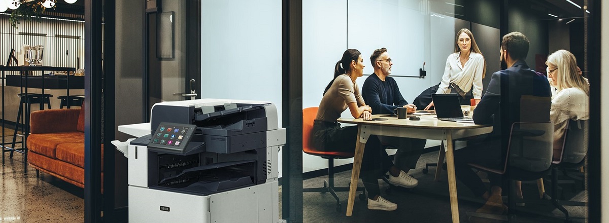 AltaLink Printer in front of conference room with people in it.