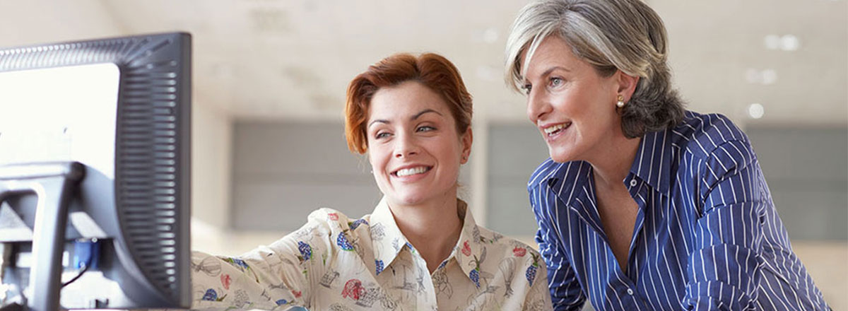 Two women looking at a monitor together. One woman is pointing at the monitor.