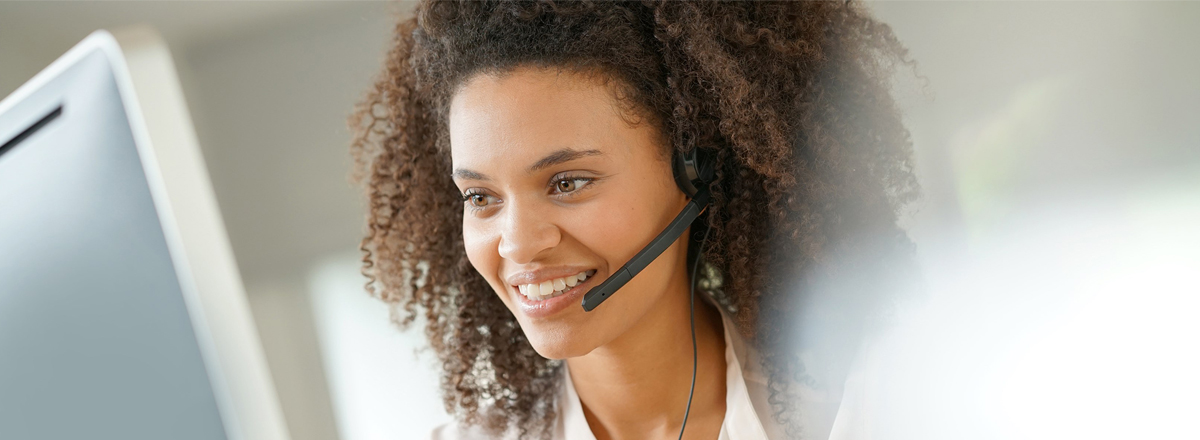 A customer service rep wearing a phone headset, looking at a computer screen