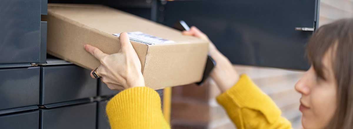 A woman taking a package from a mailbox