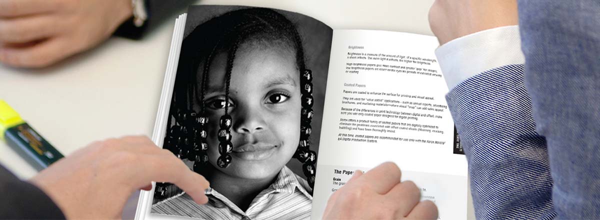 People in business suits looking at a book with a monochrome photo of a young girl