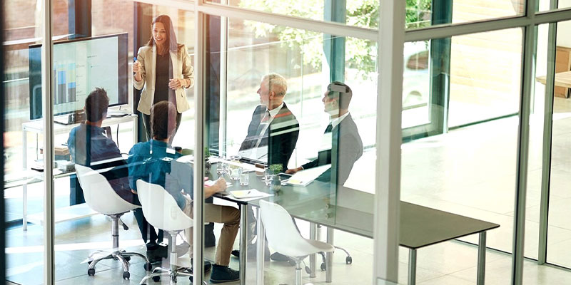 People sitting in a meeting room looking at a screen.