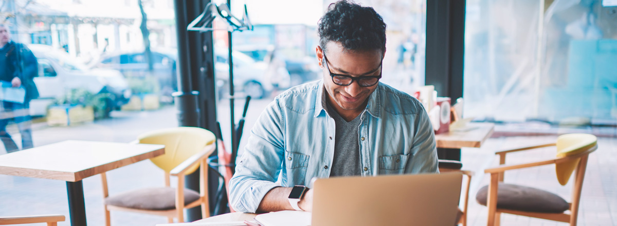 Man sitting at a coffee shop, working on a laptop