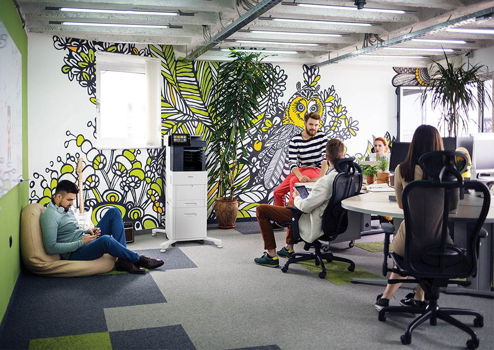 Employees in a modern office with a mural of leaves and flowers