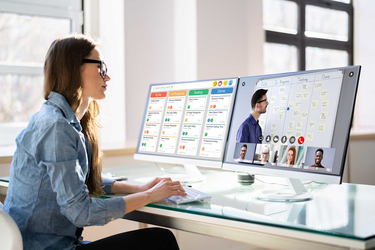 Woman with glasses on a video conference call with two monitors