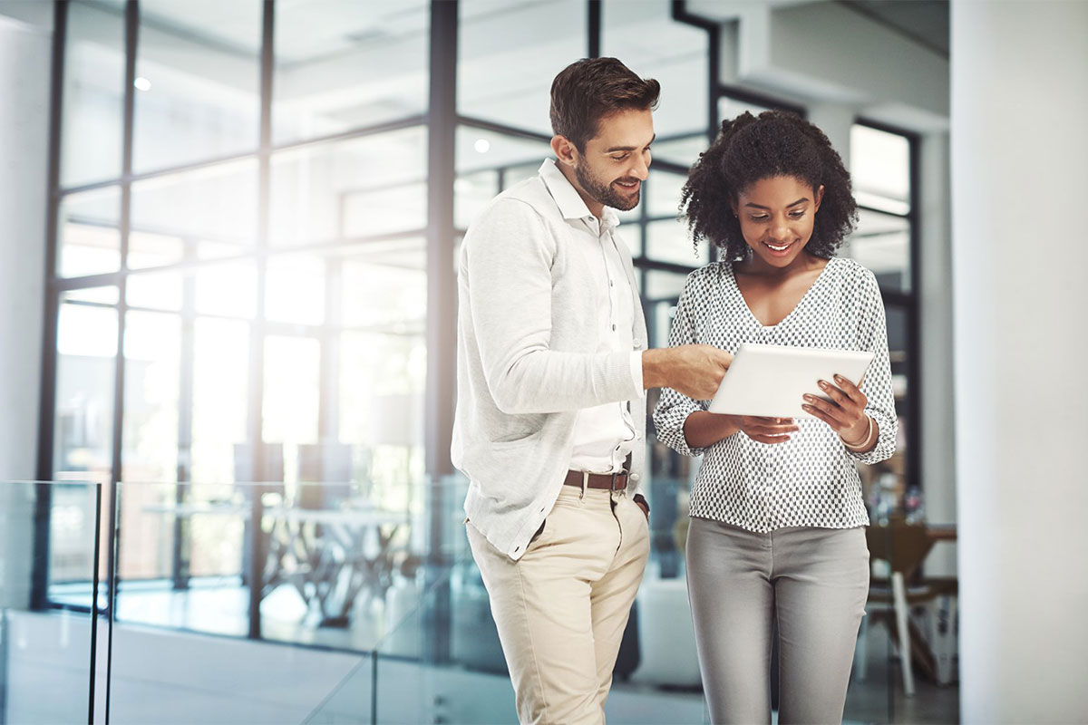 man and woman in office looking at a tablet