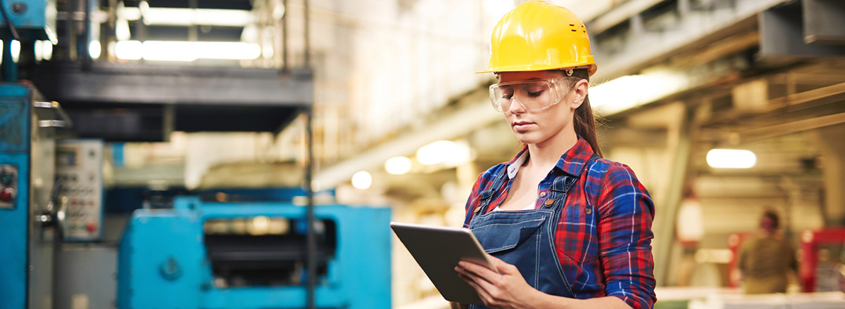 Woman in a hard hat in a warehouse, using a tablet