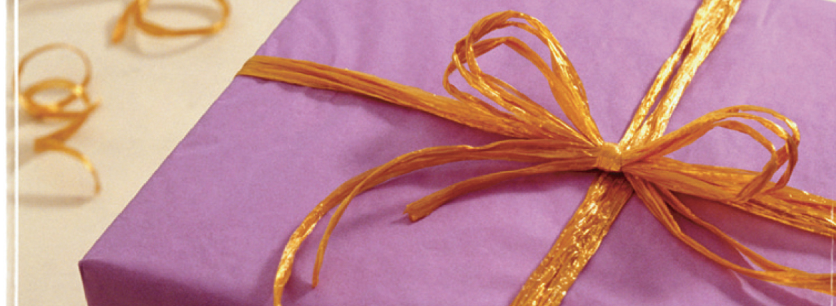 A box wrapped with purple tissue paper and a gold ribbon