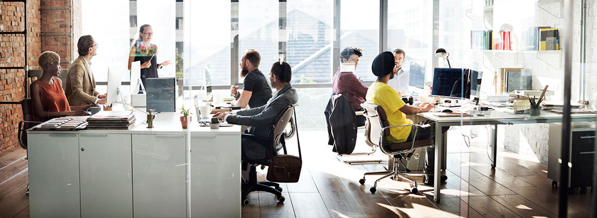 Co-workers meeting in an open, modern office with a wall of windows