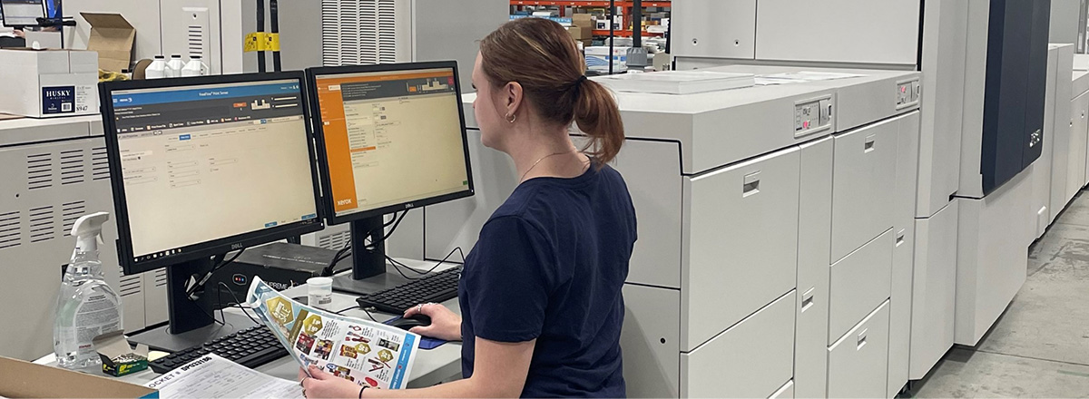 Woman in a print shop standing and working on a computer