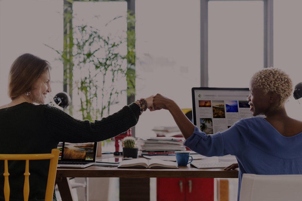 Two women in an office doing a fist bump