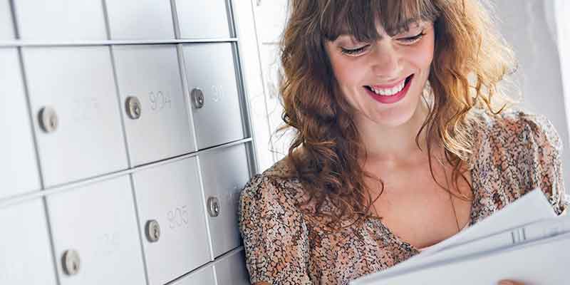 Happy woman opening mail in a post office