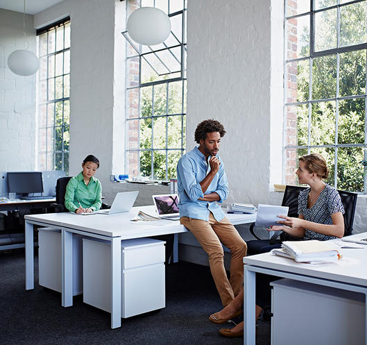 Coworkers talking in an open plan office