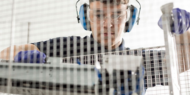 Man working behind a screen with headphones on.
