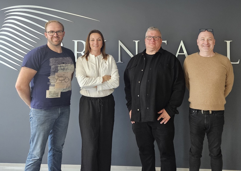 Staff of Printall AS in front of their logo printed on a wall