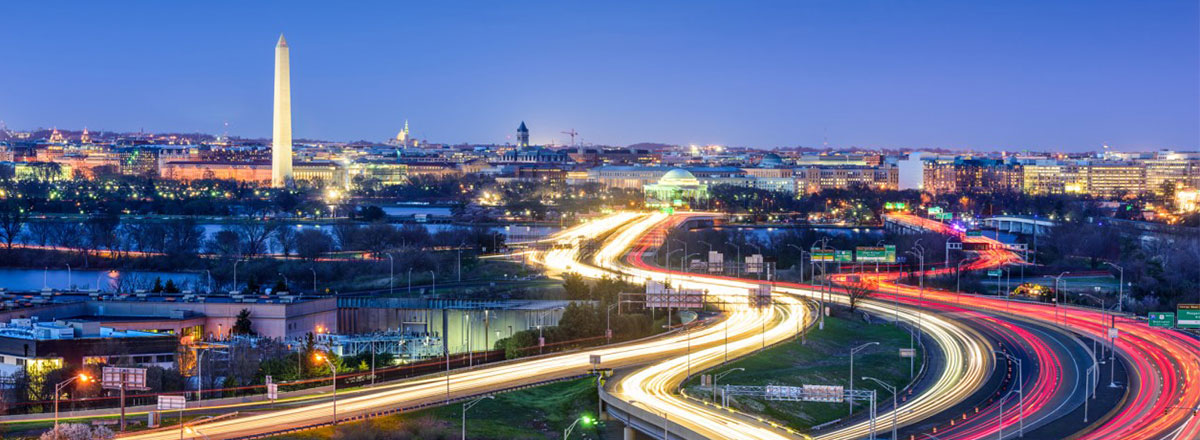 View of Washington DC from the distance, at night, with blurred lights from cars on a highway