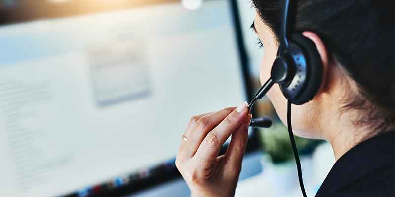 Call center rep with a headset looking at a computer