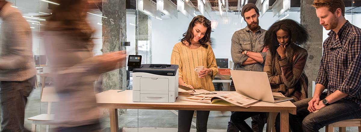 Busy office with coworkers gathered around a Xerox MFP