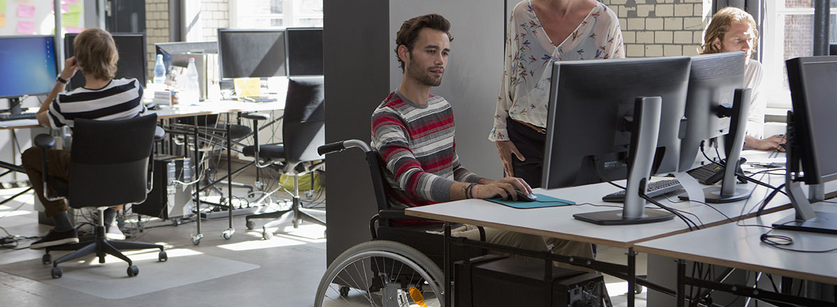 Accessible office with a man in a wheelchair at a desk with a computer