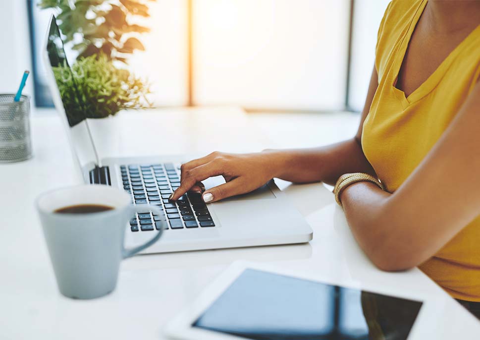 Woman working on a laptop with coffee nearby