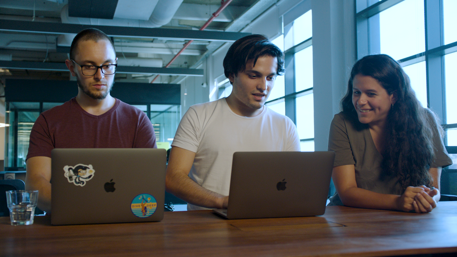 Mercado Libre's developer team smiling as they code on their laptops with GitHub Copilot.
