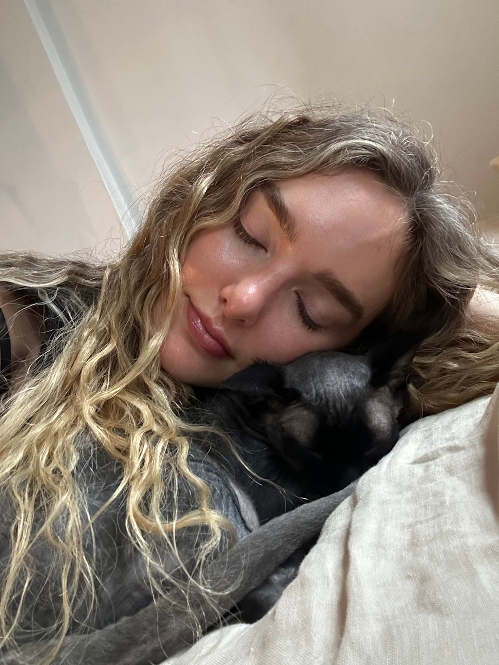 Cuddly selfie of Hannah and Norman. Hannah's wavy blonde hair cascades over Norman's torso lovingly, while her head gently rests on his.