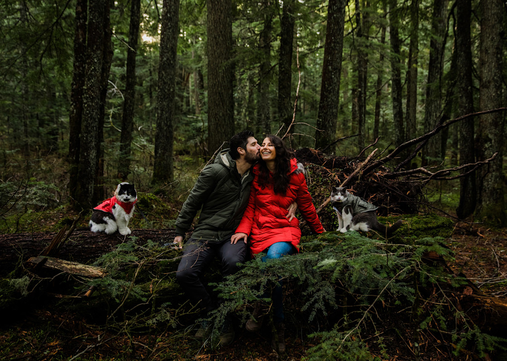 Janelle and her husband pose in the forrest for a photo with Atlas and Lyra by their sides adorned in kitty outerwear.