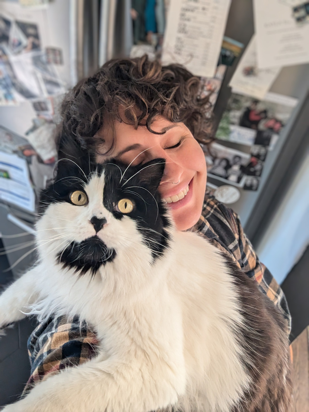 Janelle cuddles Atlas while she stands in the kitchen cooking.