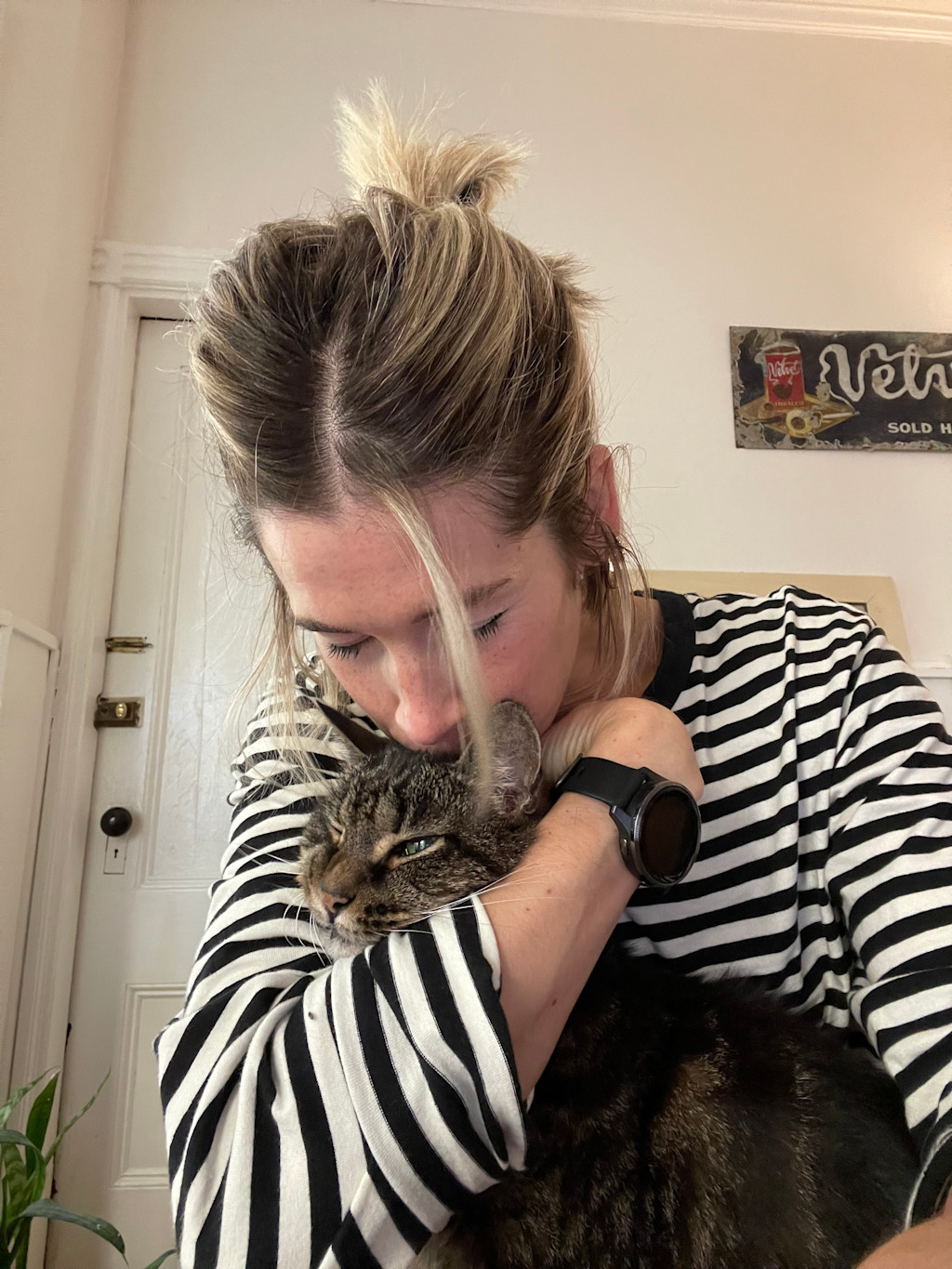 Julie is wearing a long-sleeve black & white shirt is hugging Zeb closely while kissing him on the head. A piece of her blonde hair drapes down naturally over her face.